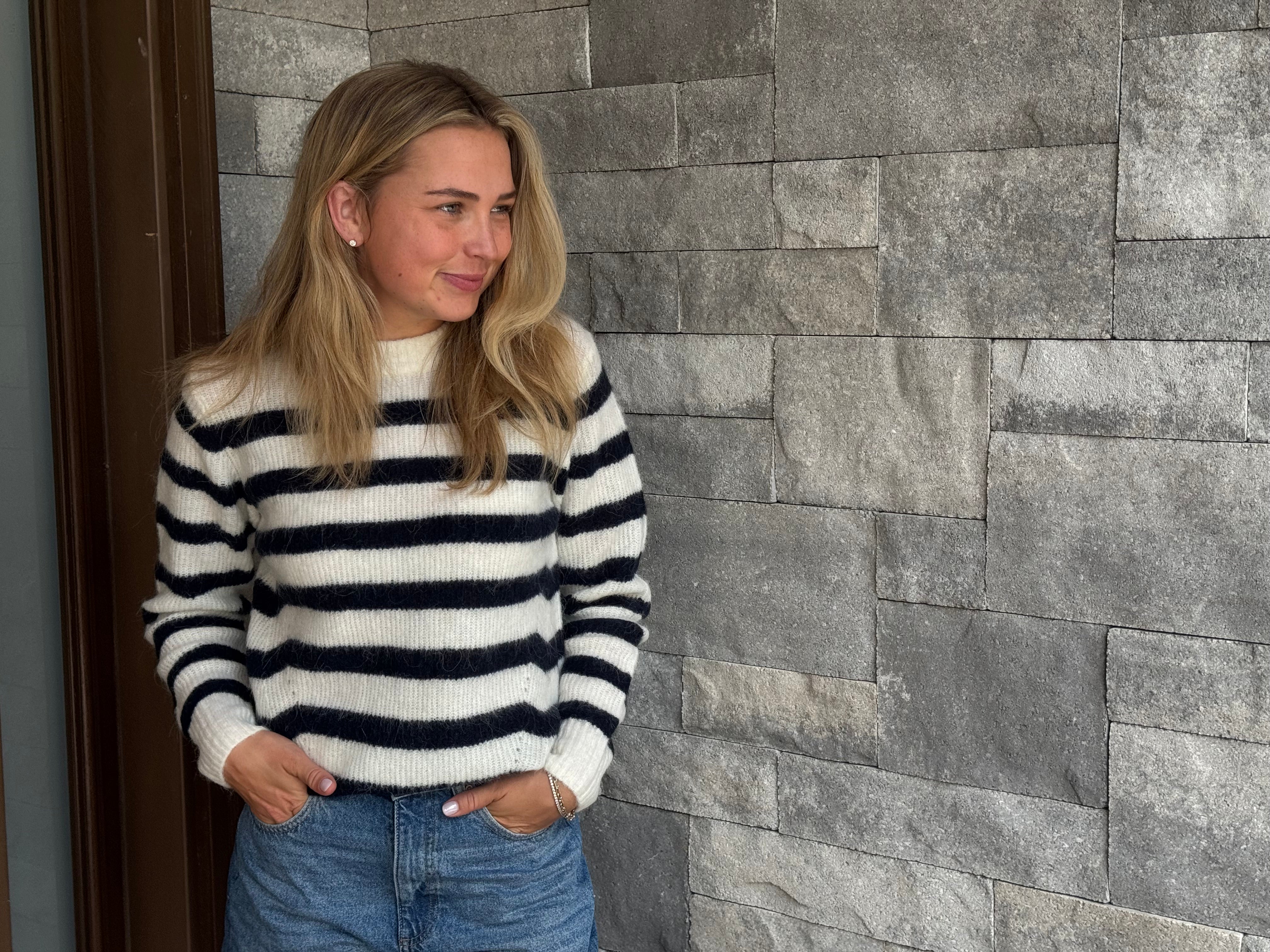 Woman wearing a black and white striped sweater against a stone wall. In the Kawartha Lakes. 
